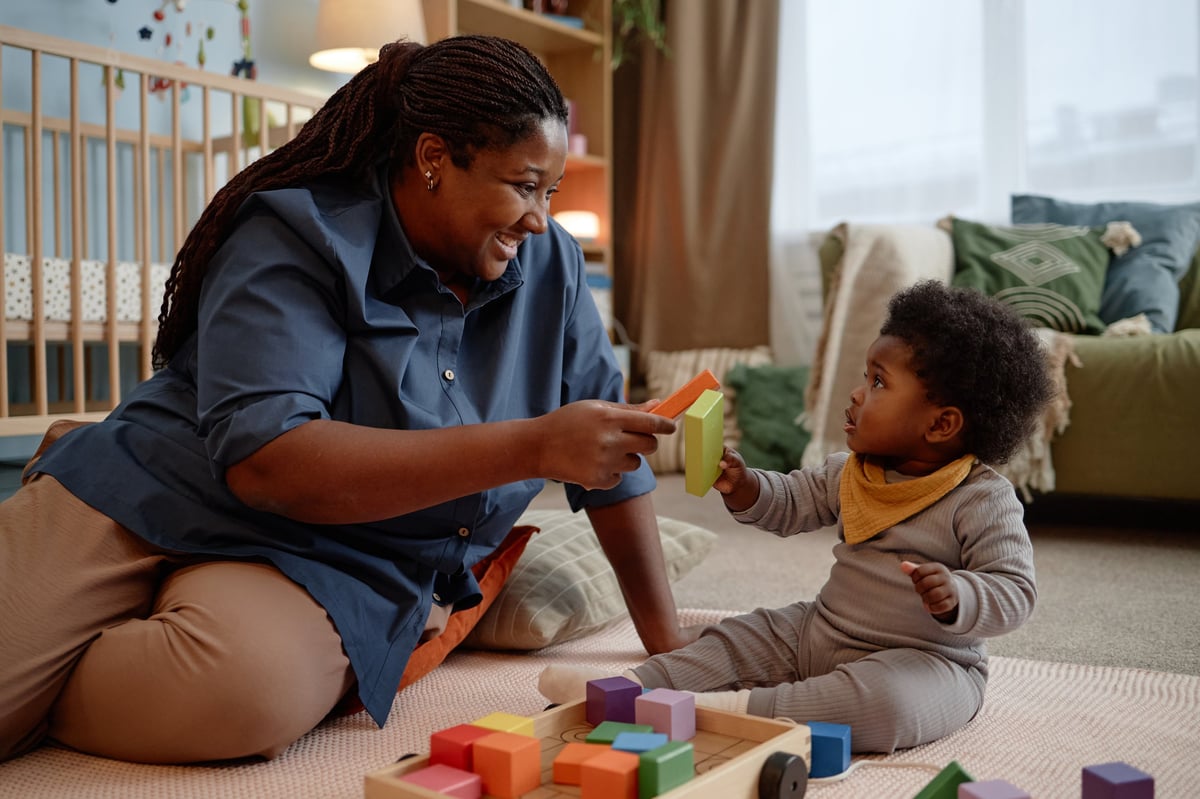 Smiling woman looking at little daughter with love and affection